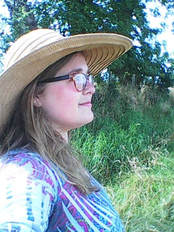 Picture. A white woman with blonde hair wearing a straw hat and glasses.